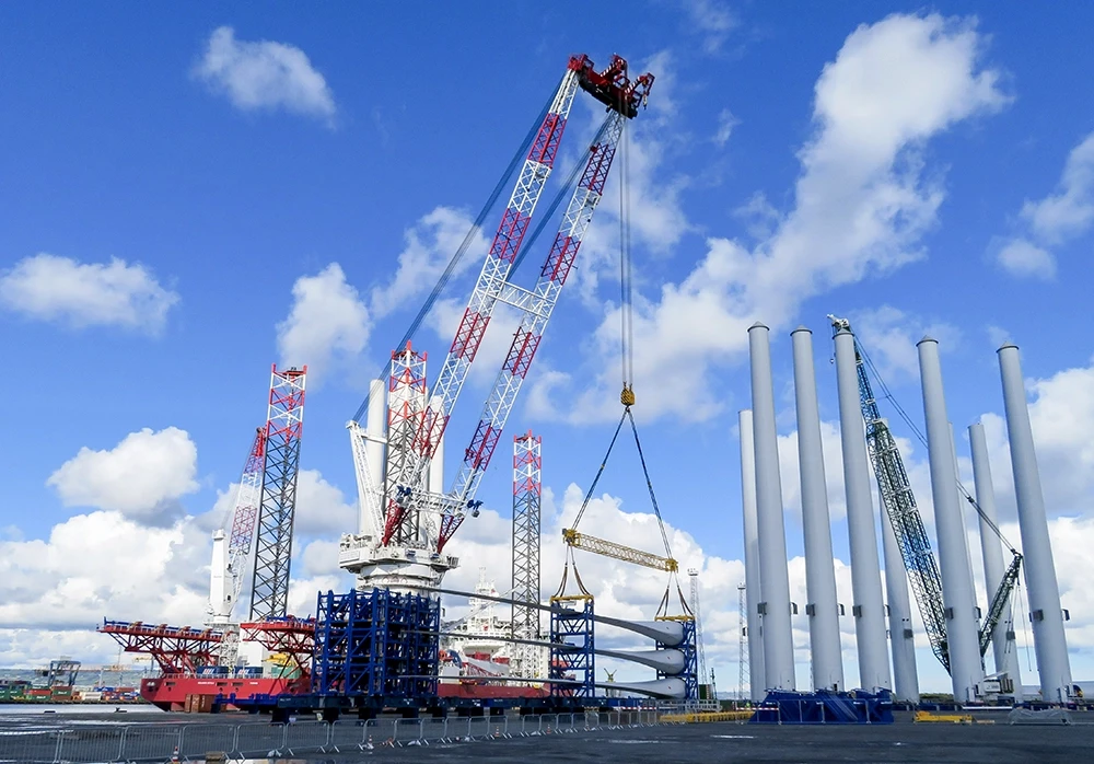 Cranes lifting and positioning large offshore components during quayside sea fastening operations