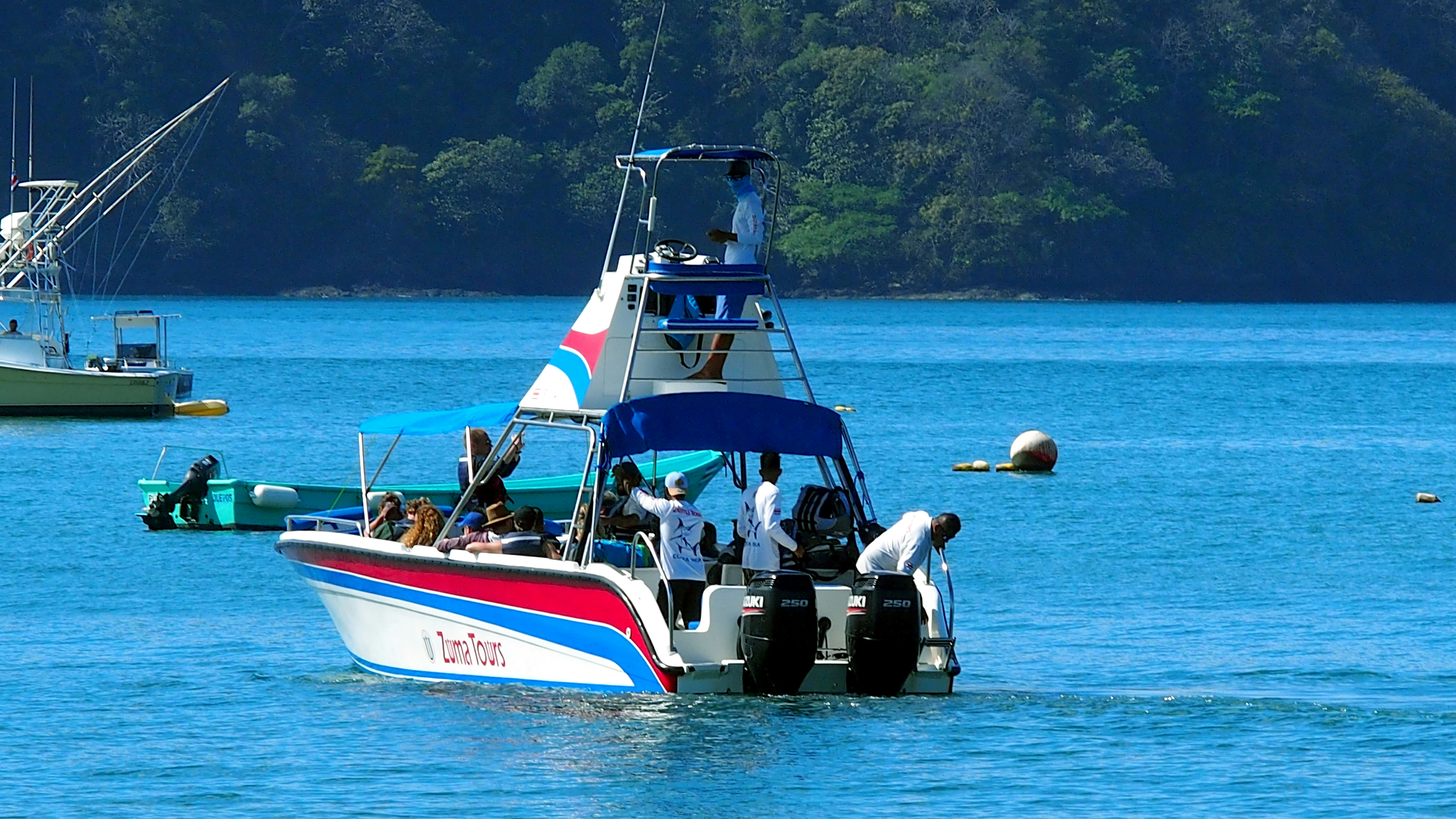 Boat with people in the water, "Zuma Tours" visible.