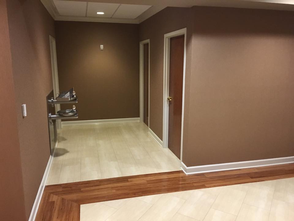 Interior view of a hallway with brown walls, wooden flooring, and doors leading to different rooms.