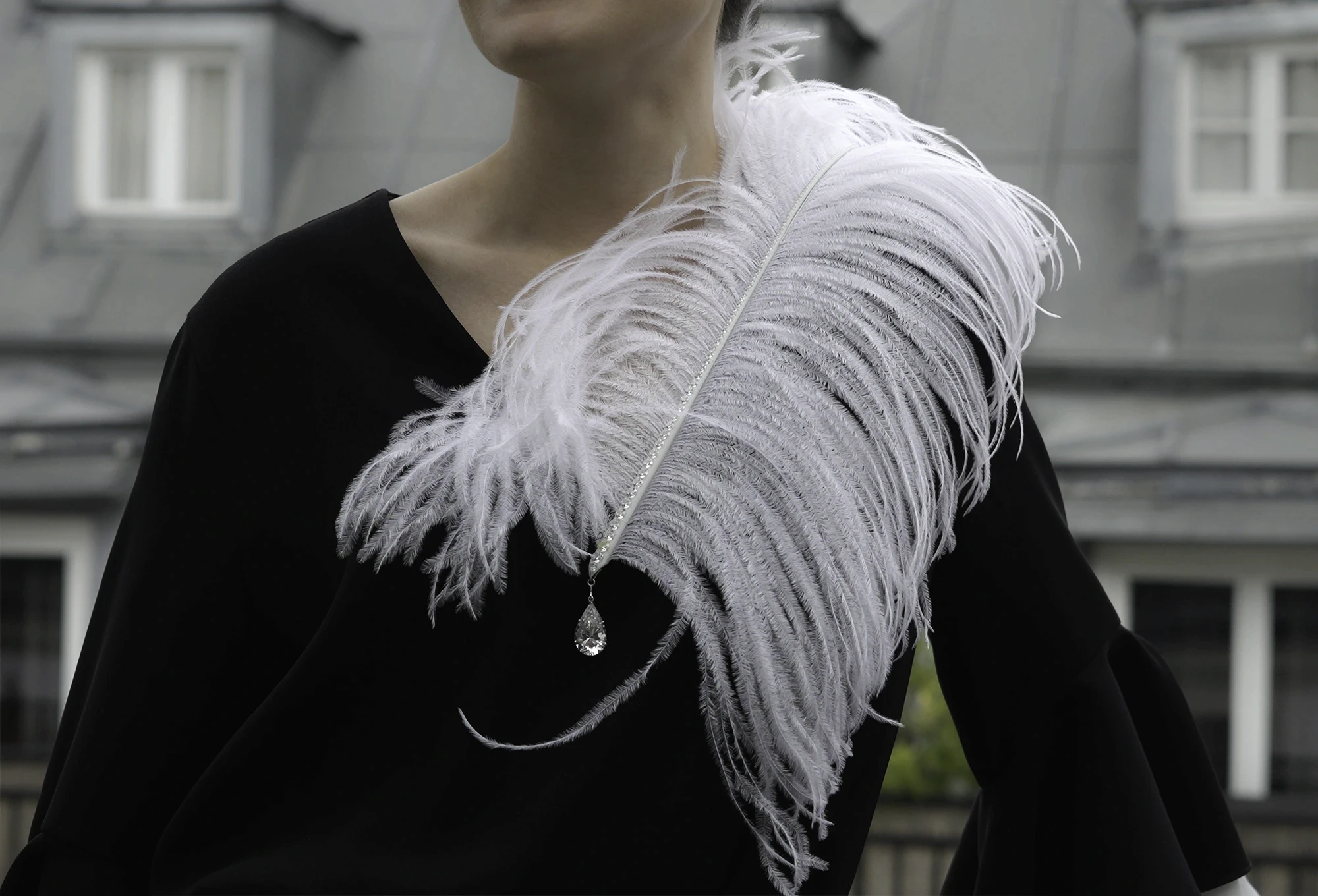 Broche Plume Maison Édéenne en or blanc et diamants portée sur une tenue noire
