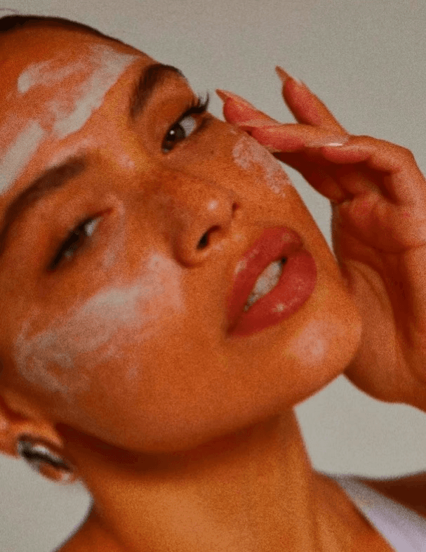 Model applying face cleanser scrub during skincare routine