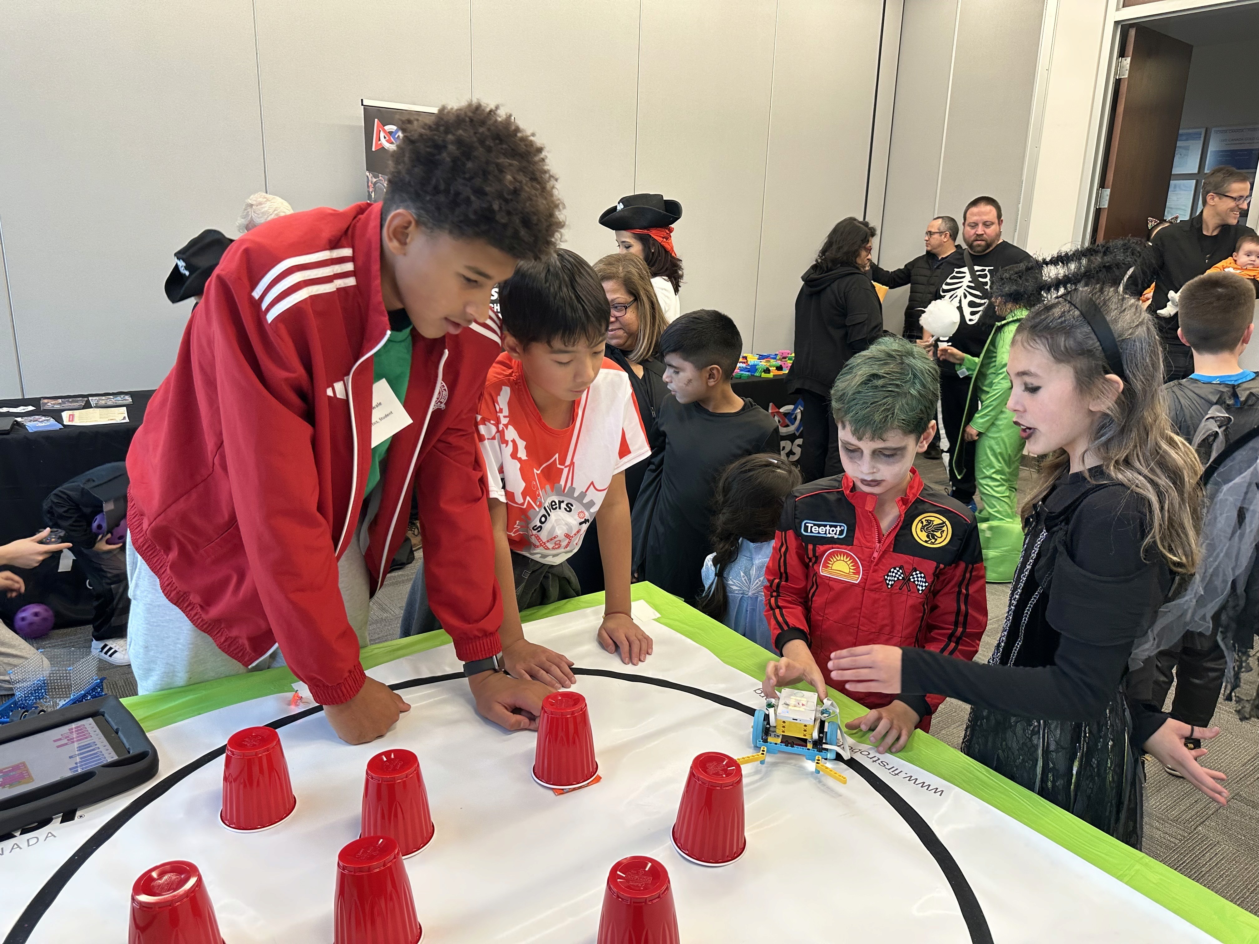 SolversMind FLL students, Samuel Pan and Amani showcase FIRST robotics programs to Honda employees and families during the 2025 Halloween celebration.