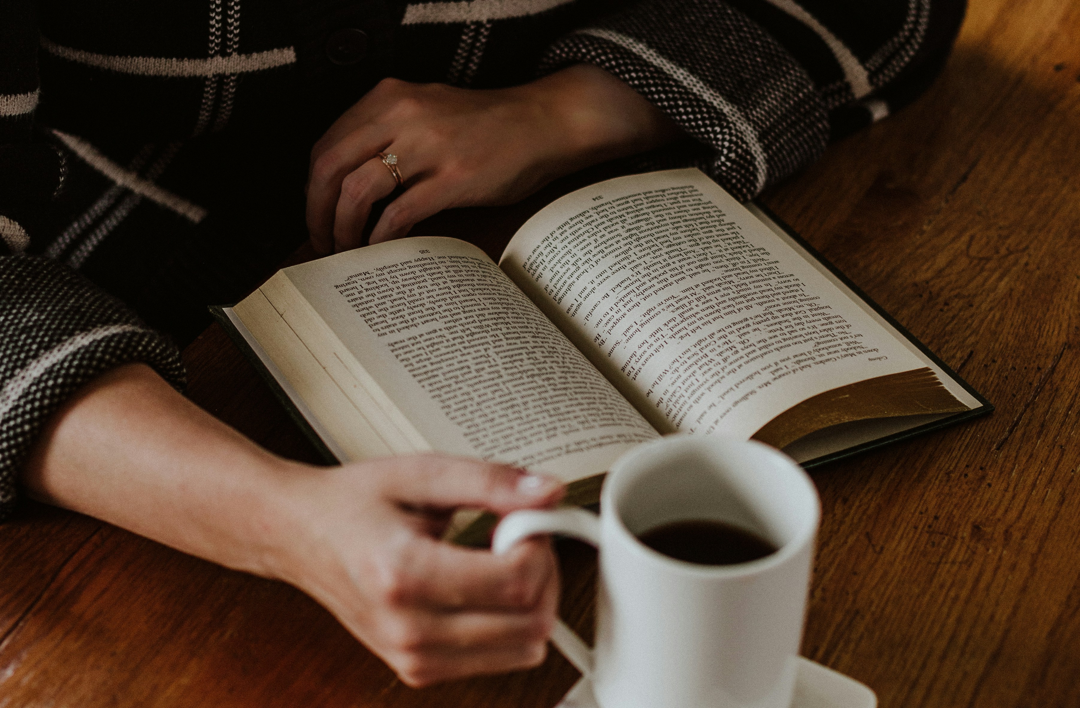 A person sitting on the floor with a book and a cup of coffee