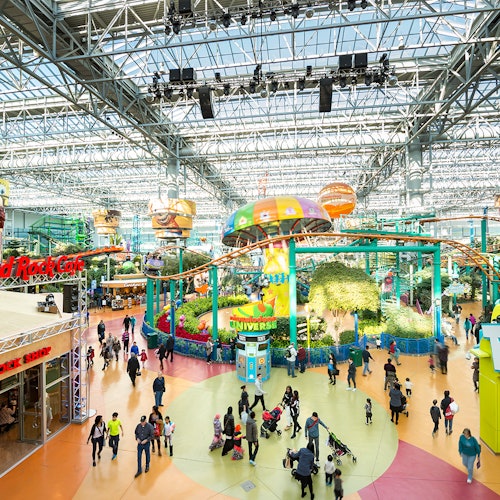 一個繁忙的室內遊樂園，裡面有色彩繽紛的遊樂設施、景點，還有很多人走來走去。可以看到Hard Rock Café的招牌。