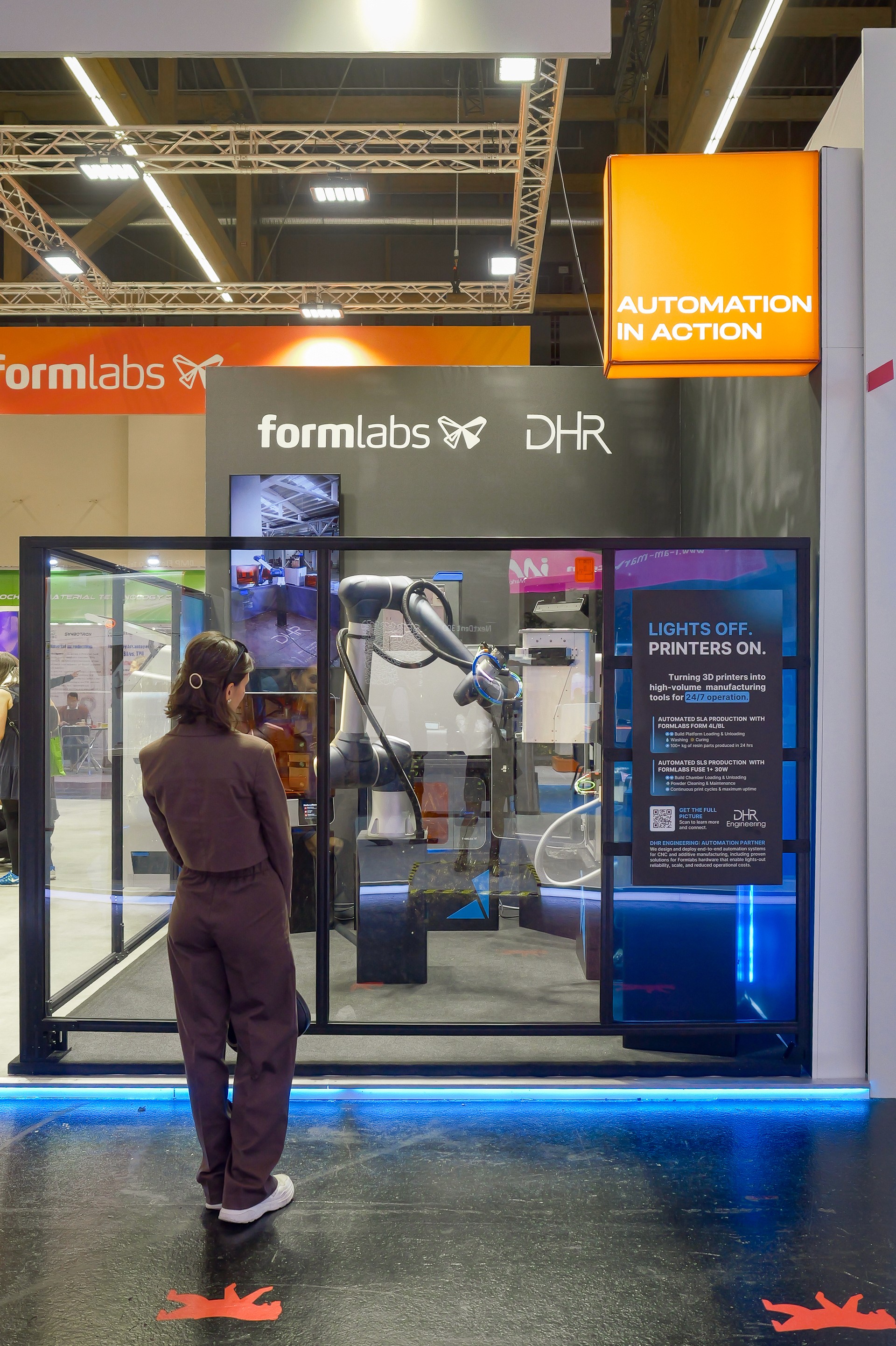 Front view of the automated cell with a person looking at the presentation board and big sign "Automation in action"