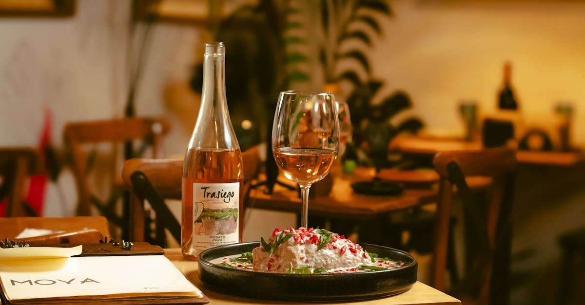 A sophisticated restaurant ambiance featuring rosé wine and a gourmet dish in a dimly lit setting.