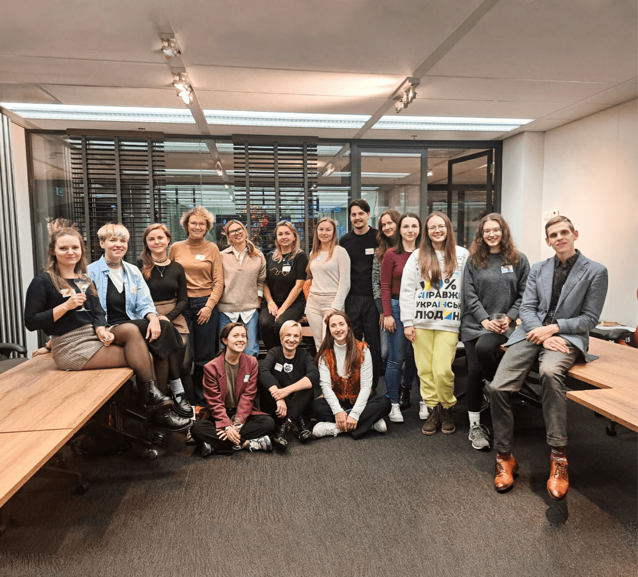 Group photo of Ukrainian local community leaders in the Netherlands, seated and standing together indoors during a leadership strengthening event.