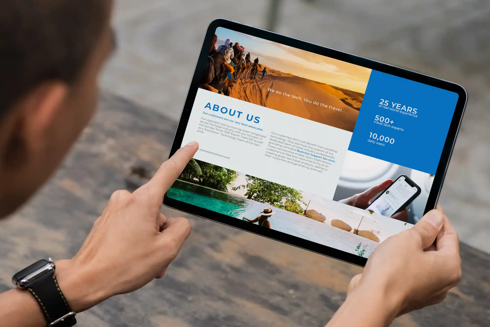 Person holding a tablet displaying Open Destinations’ “About Us” page, showing travel images, company milestones, and information about their global operations.