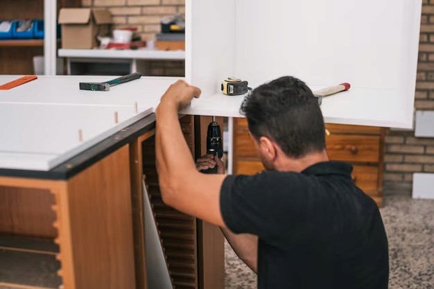Person assembling a cabinet with a drill. Carpenter working on a DIY project. Furniture assembly.