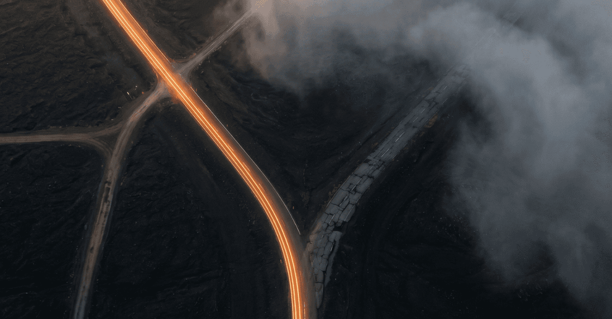 Vista aérea de estradas se bifurcando à noite: um caminho com trilhas de luz intensa, outro no escuro — metáfora visual sobre a divisão entre modelos de IA com reasoning em aceleração e modelos sem reasoning estagnados