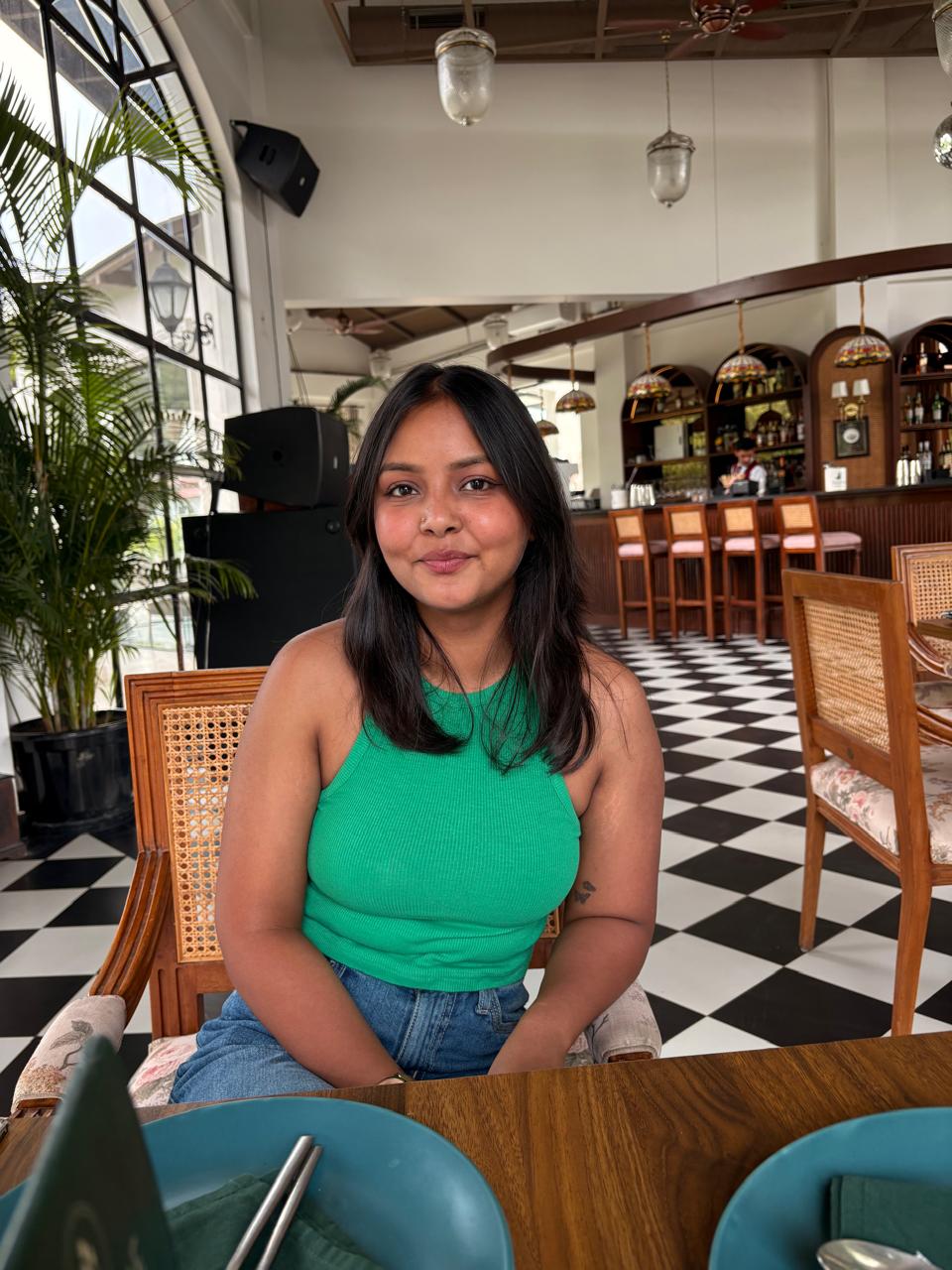 Woman working on a laptop computer at a table in a bright room.