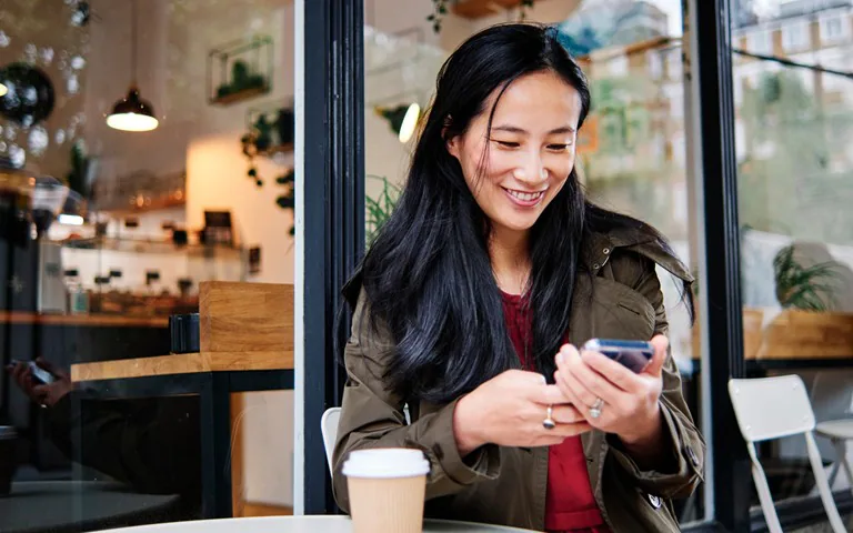 Asian woman looking at her phone happy