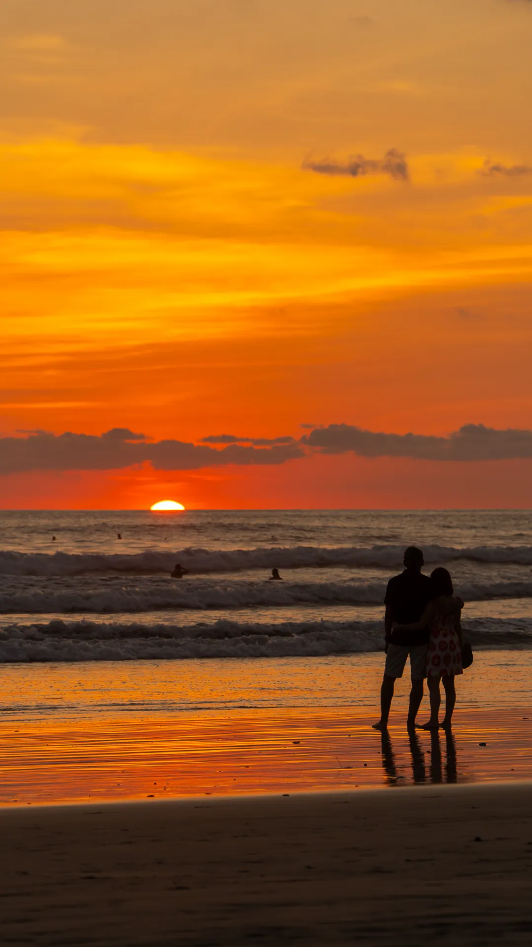 Couple watching an orange sunset over the ocean in Manzanillo, Costa Rica