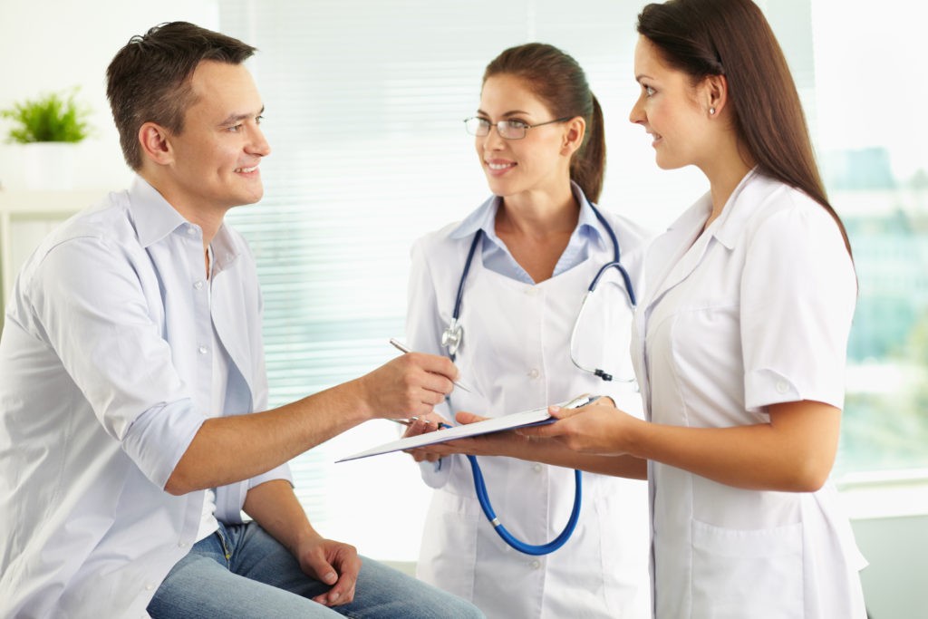 Male patient discussing new patient form with female doctor