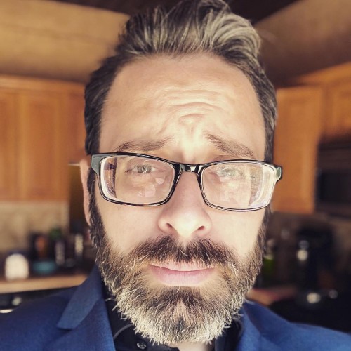 A thoughtful young person with dark hair gazes to the side, captured in soft black and white lighting.