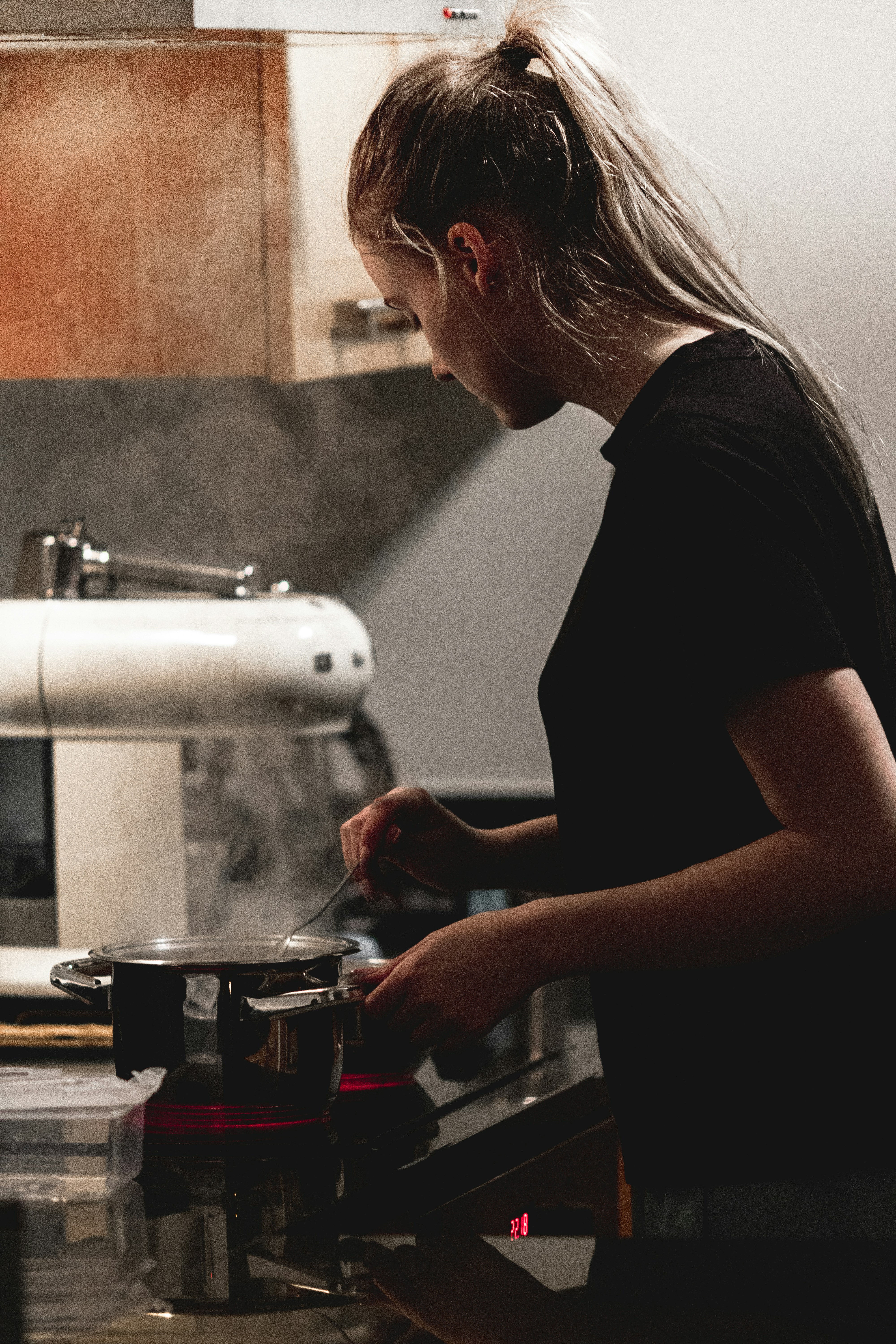 woman in black t-shirt pouring coffee on clear glass mug
