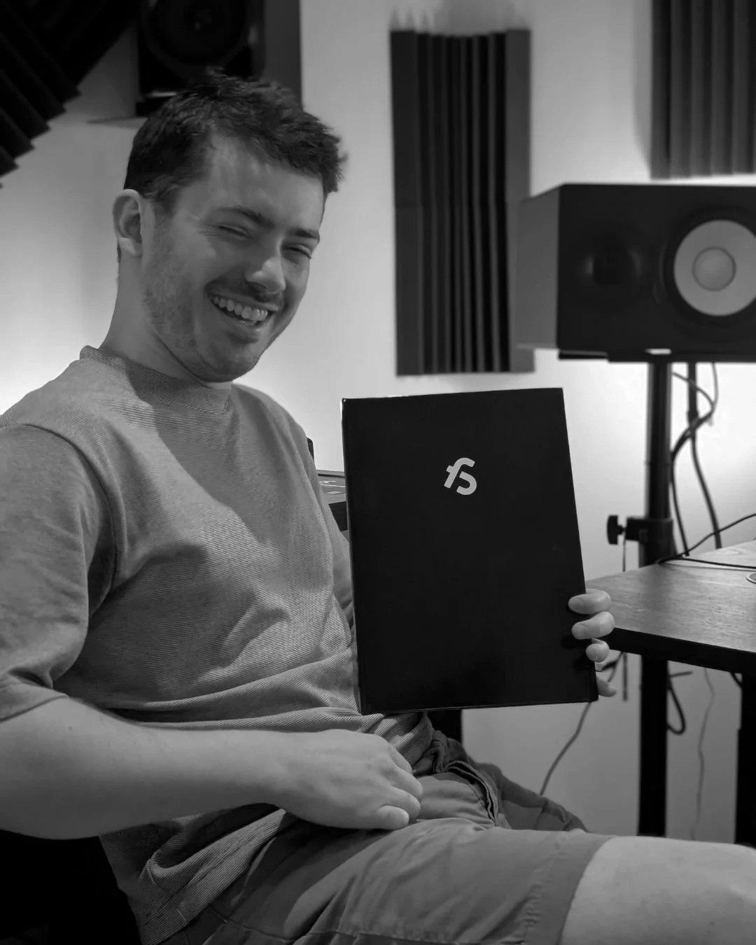 A DJ standing at a mixing board, wearing headphones and a white t-shirt, working with Pioneer DJ equipment.