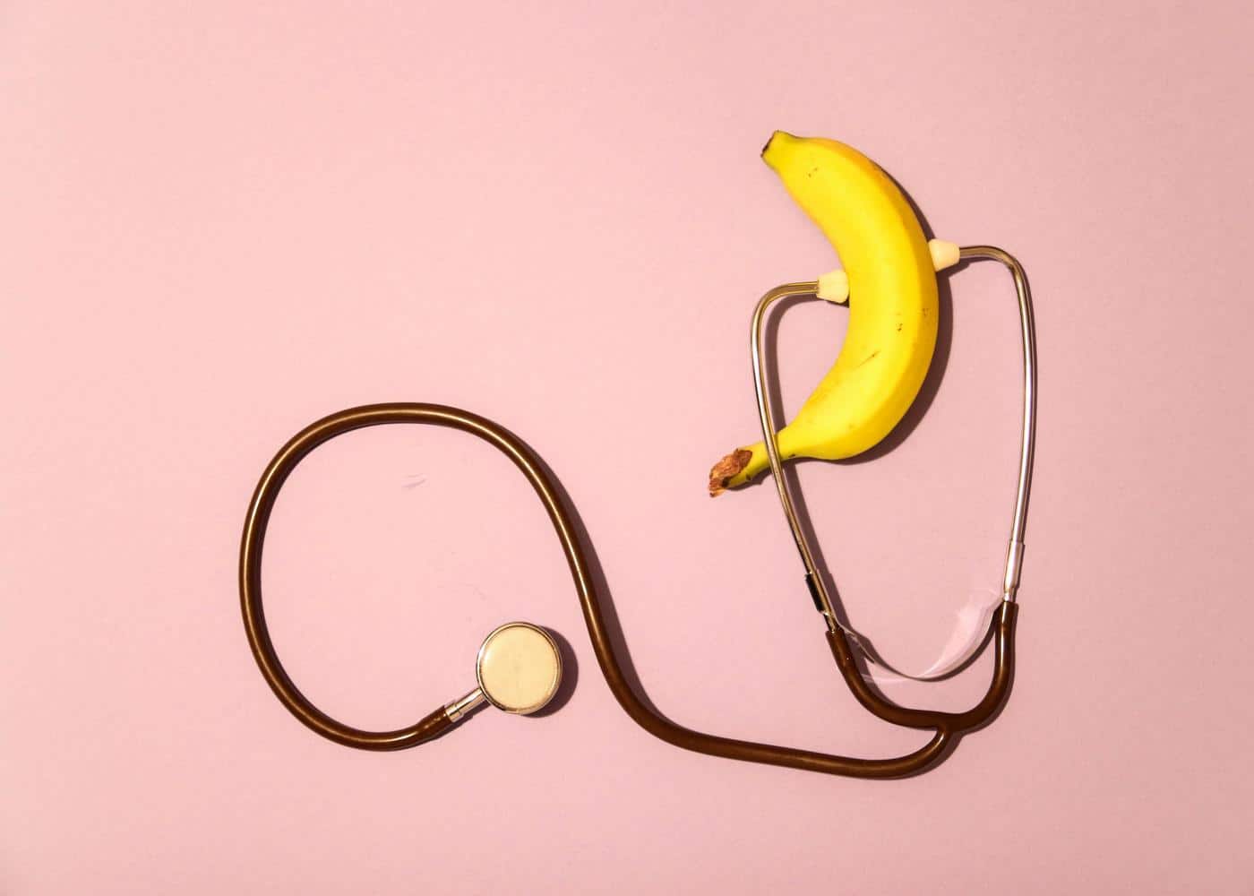 What are the causes of ED? Stephoscope and banana on a pink background