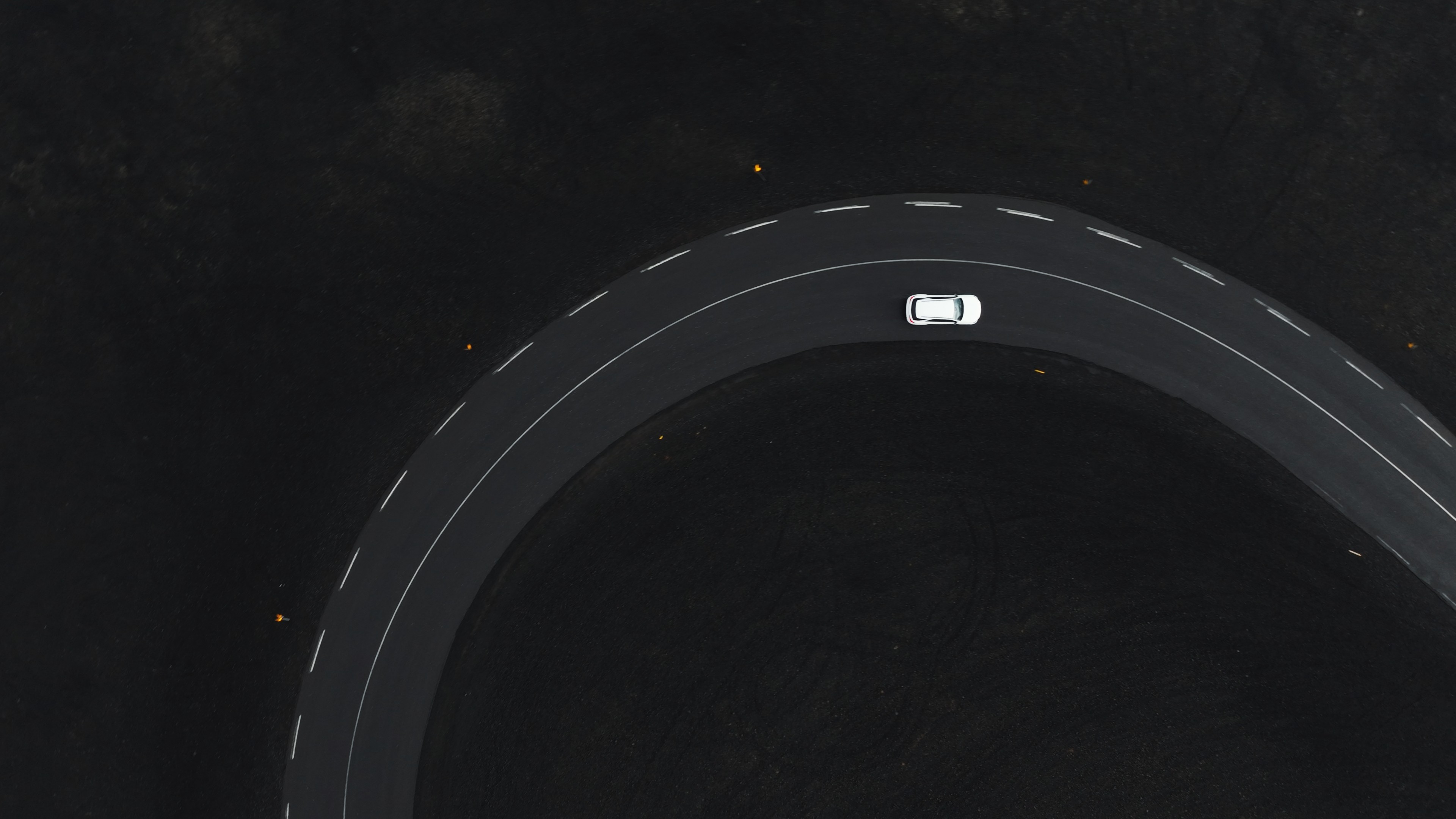 Aerial view of a car on a winding road through black Icelandic lava