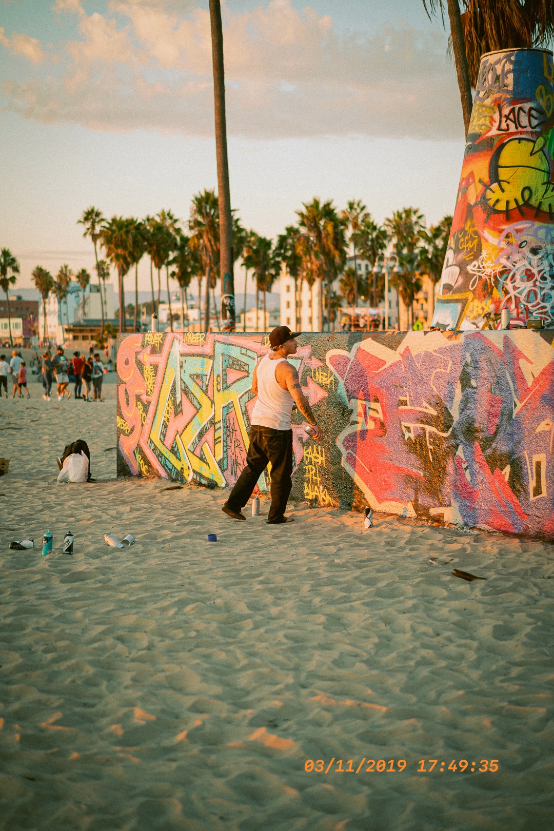 Artiste de rue créant un graffiti coloré sur la plage de Venice Beach.