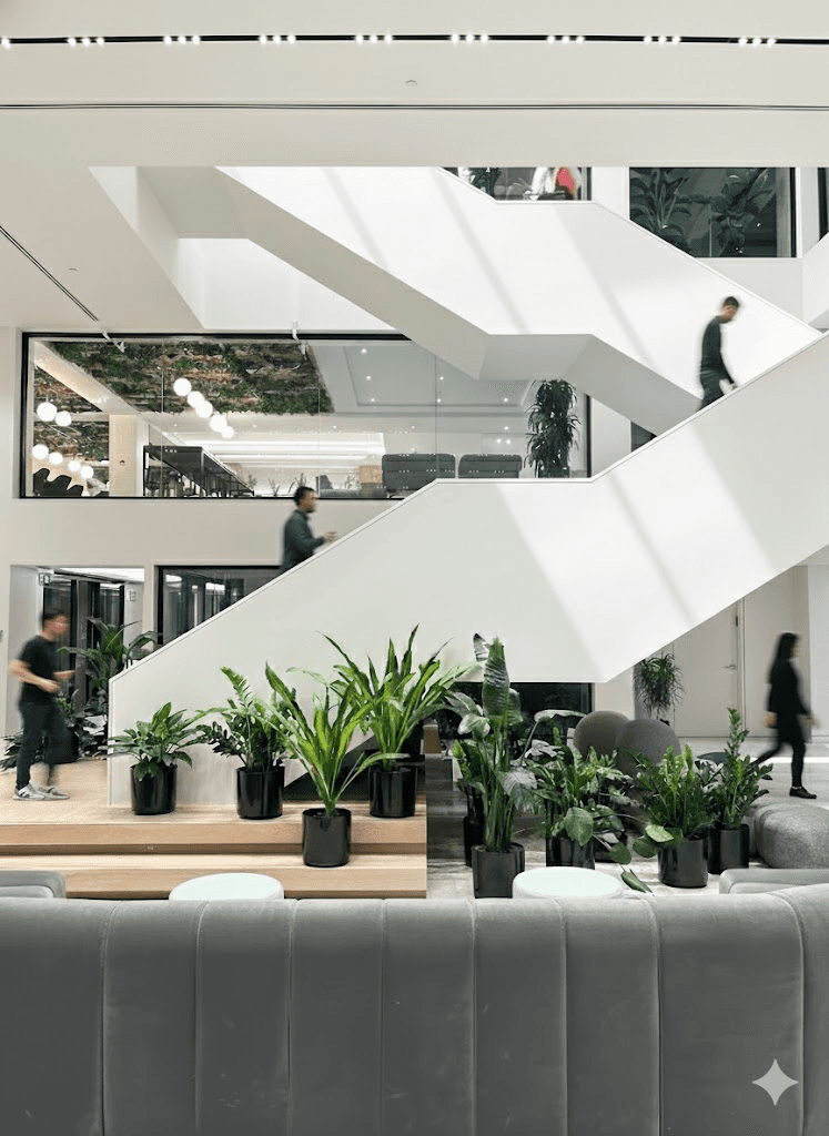 Modern office interior with glass walls, wooden accents, and a person walking up a staircase in motion blur.