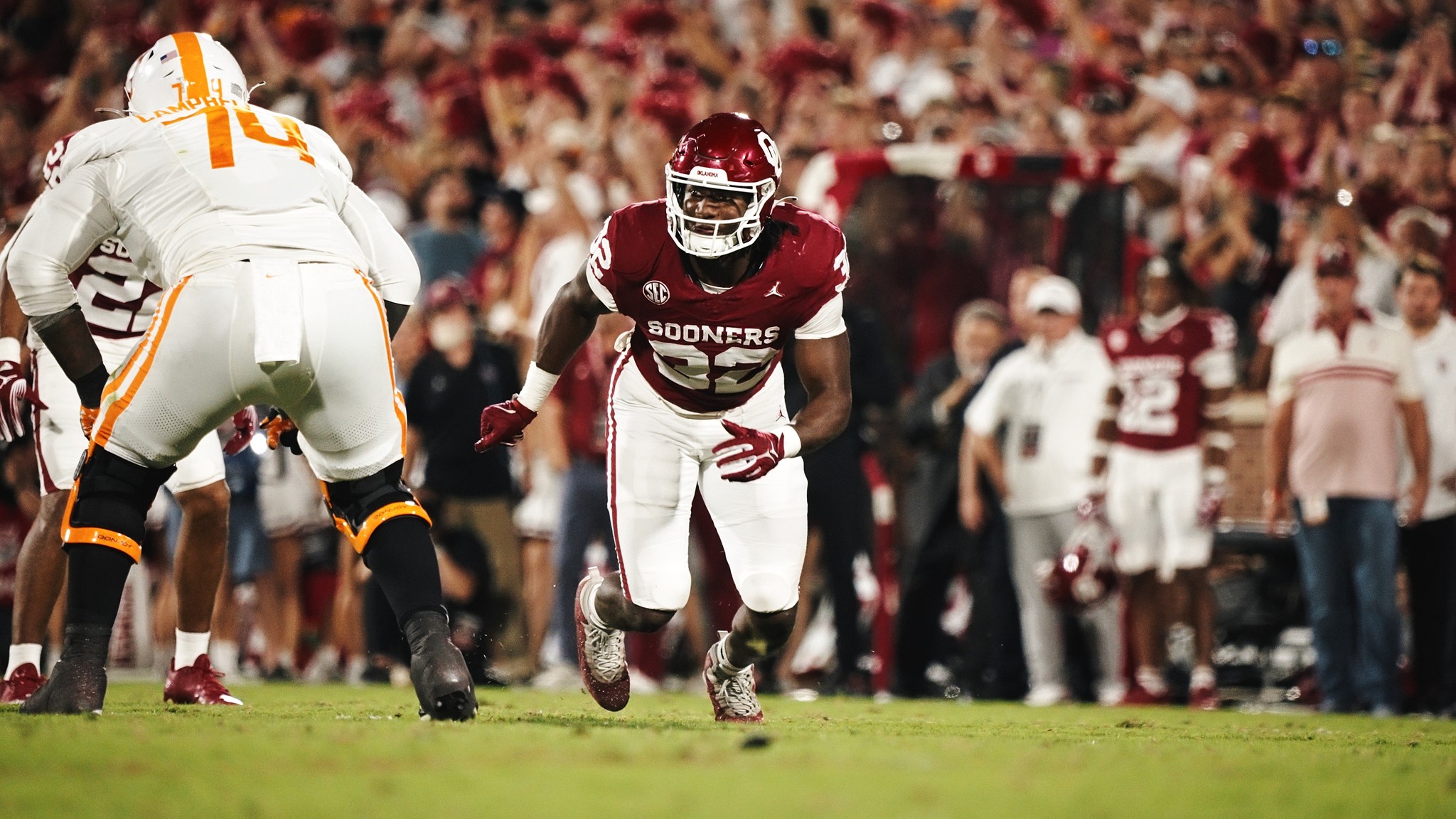 Oklahoma football player about to tackle a Tennessee player during a night game under stadium lights.