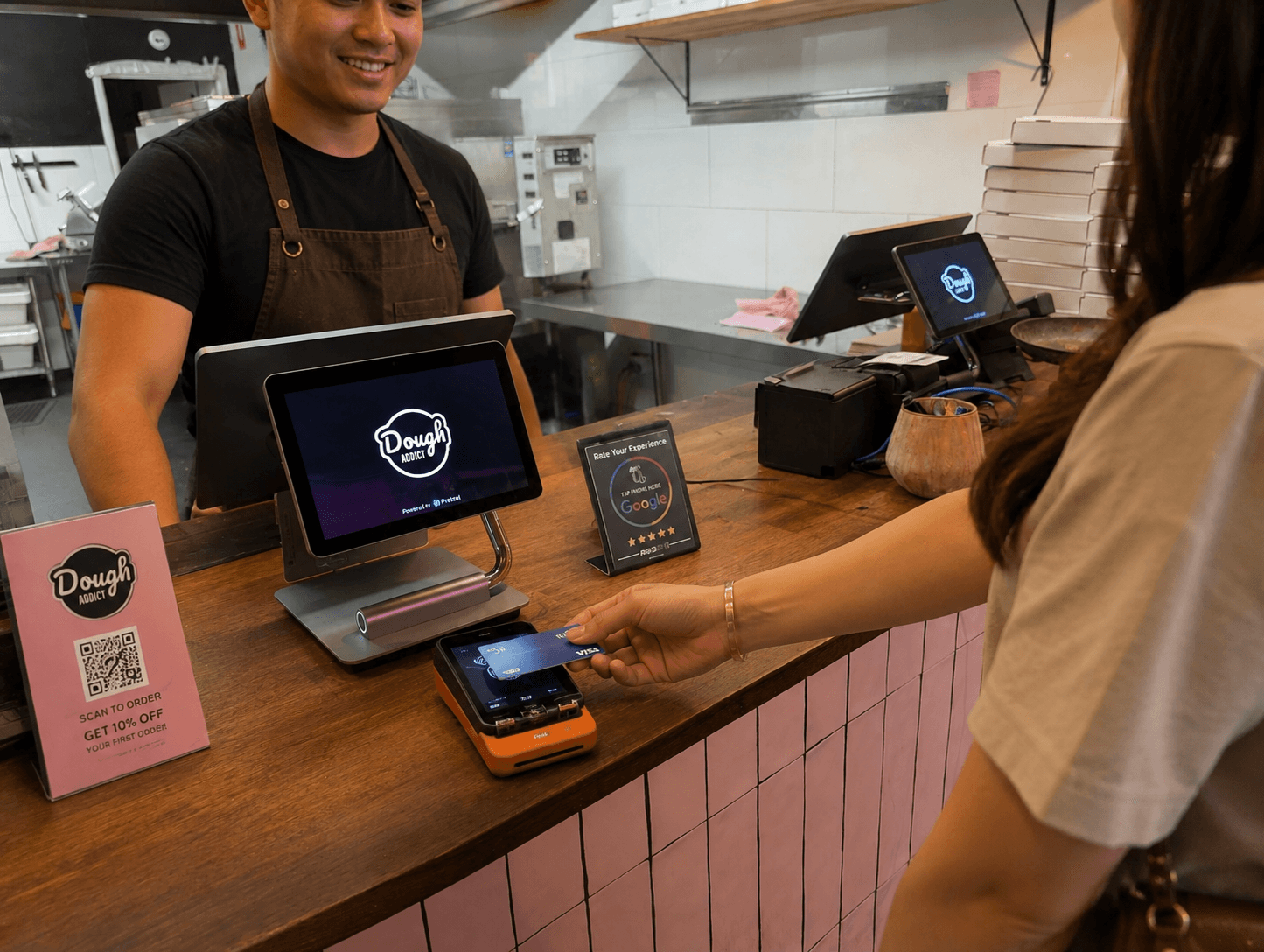 A close-up of a hand holding a credit card in front of a laptop, with another hand using a smartphone displaying a financial app. The app screen shows a digital Breezy card with a balance of $16,058.94, highlighting the availability of both physical and digital cards for seamless transactions.