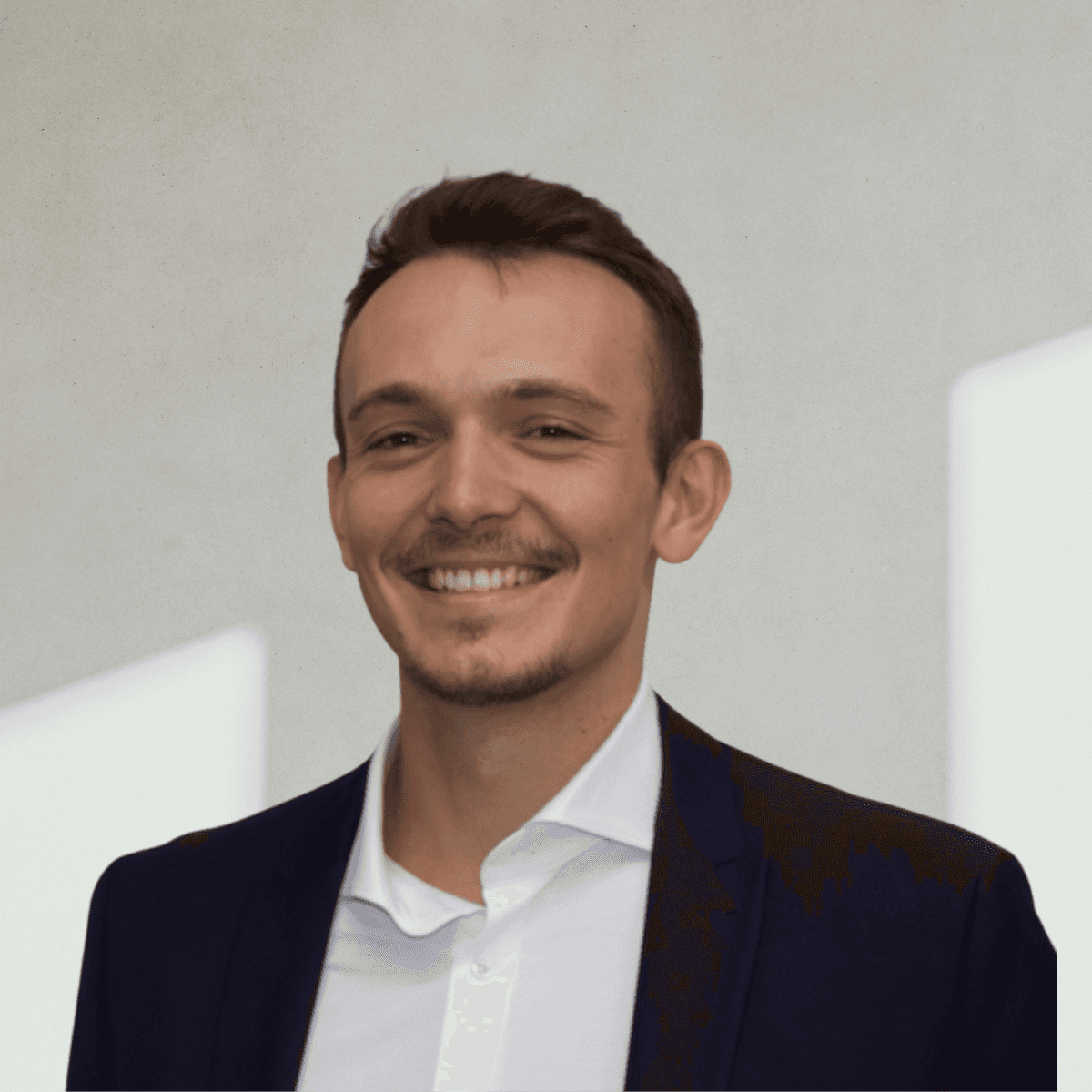 A young woman with long hair smiles while standing against a green backdrop, wearing a casual dark sweater.