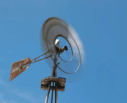 Spinning windmill against a clear blue sky on a windy day.