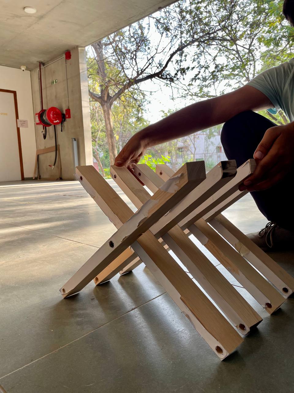 Close-up of a modern building facade featuring vertical wooden panels and black-framed windows, with natural light casting tree shadows on the surfaces.