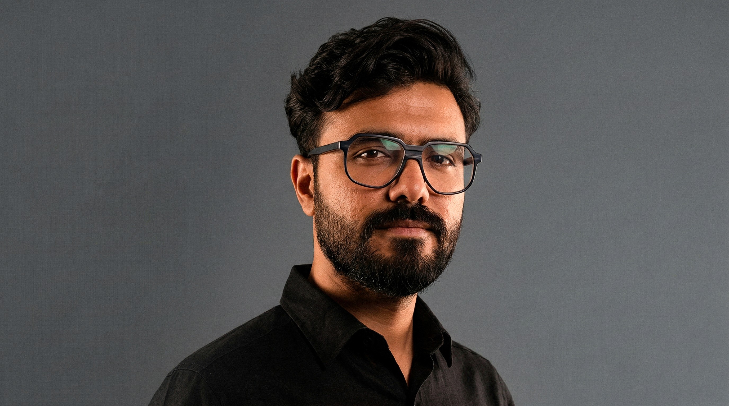 A thoughtful young person with dark hair gazes to the side, captured in soft black and white lighting.