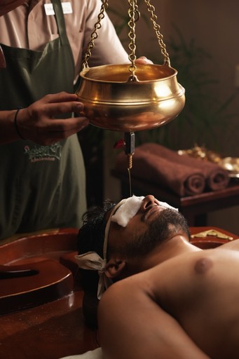 Remove Stress & Strain — Shirodhara Ayurvedic therapy with a steady stream of warm herbal oil flowing onto the forehead, promoting deep relaxation, mental clarity, and stress relief at Au Revoir Wellness Resort