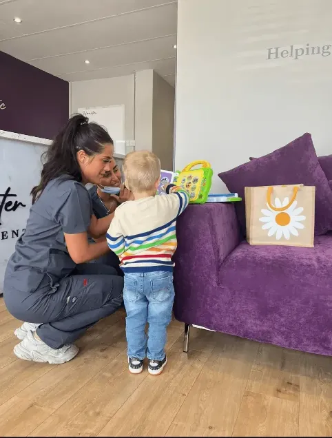 Sophie, our dental nurse, sitting and reading a book to a child whilst they visited the practice.