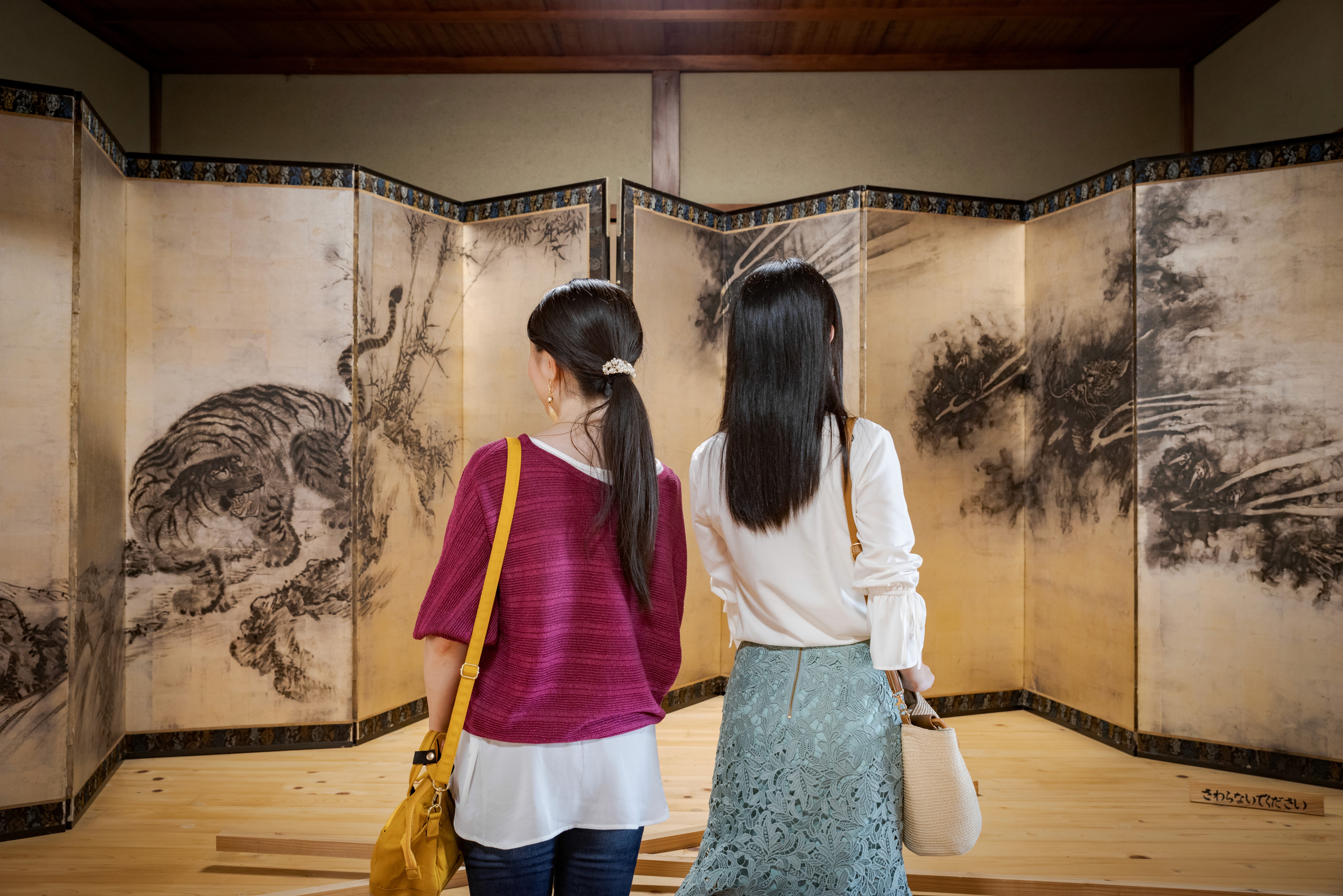 Two women admiring Japanese art work in a tatami room