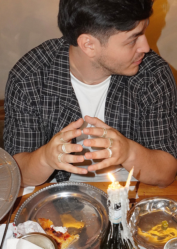 Man sitting at a table with a lit candle and pizza slices in front of him