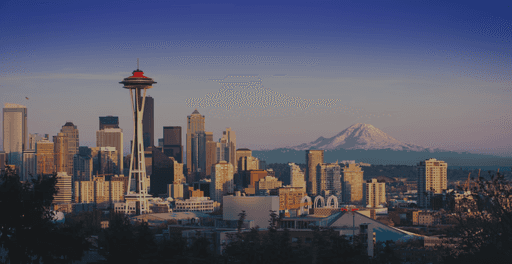 A sunset view of Seattle's skyline, featuring the Space Needle and mountains in the distance.