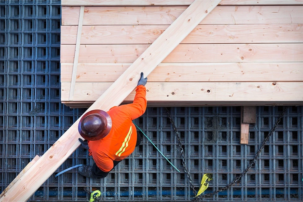 Construction worker in PPE moving lumber at a Stockton, California job site