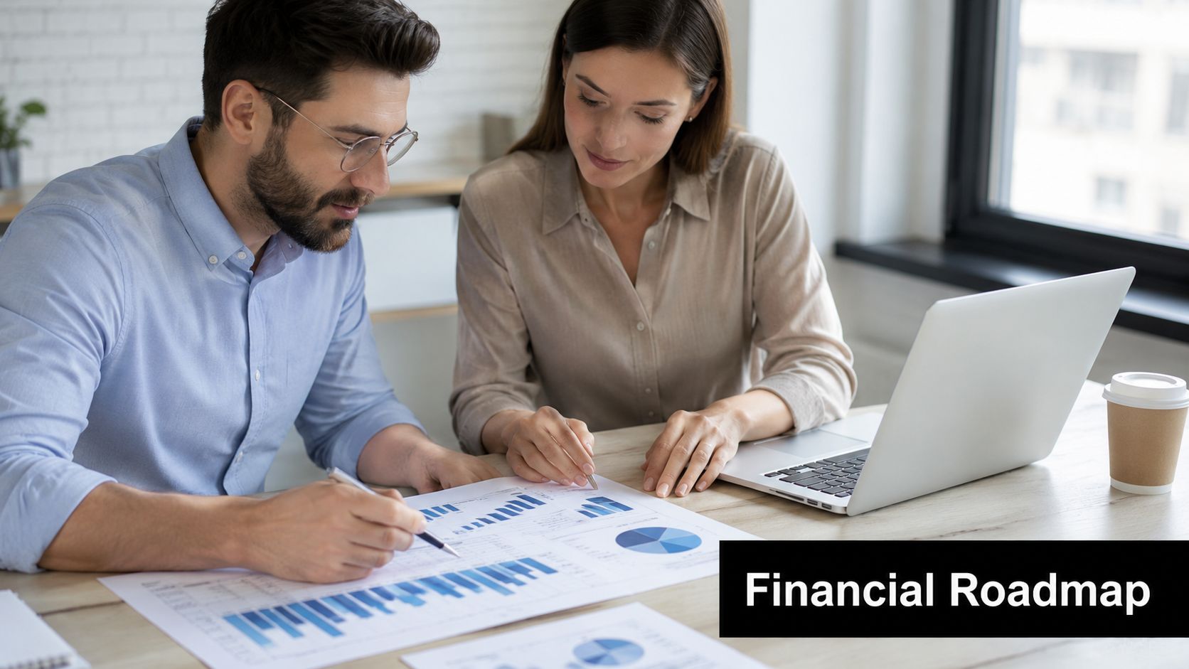 A professional man and woman reviewing financial charts and data on a desk together in an office.