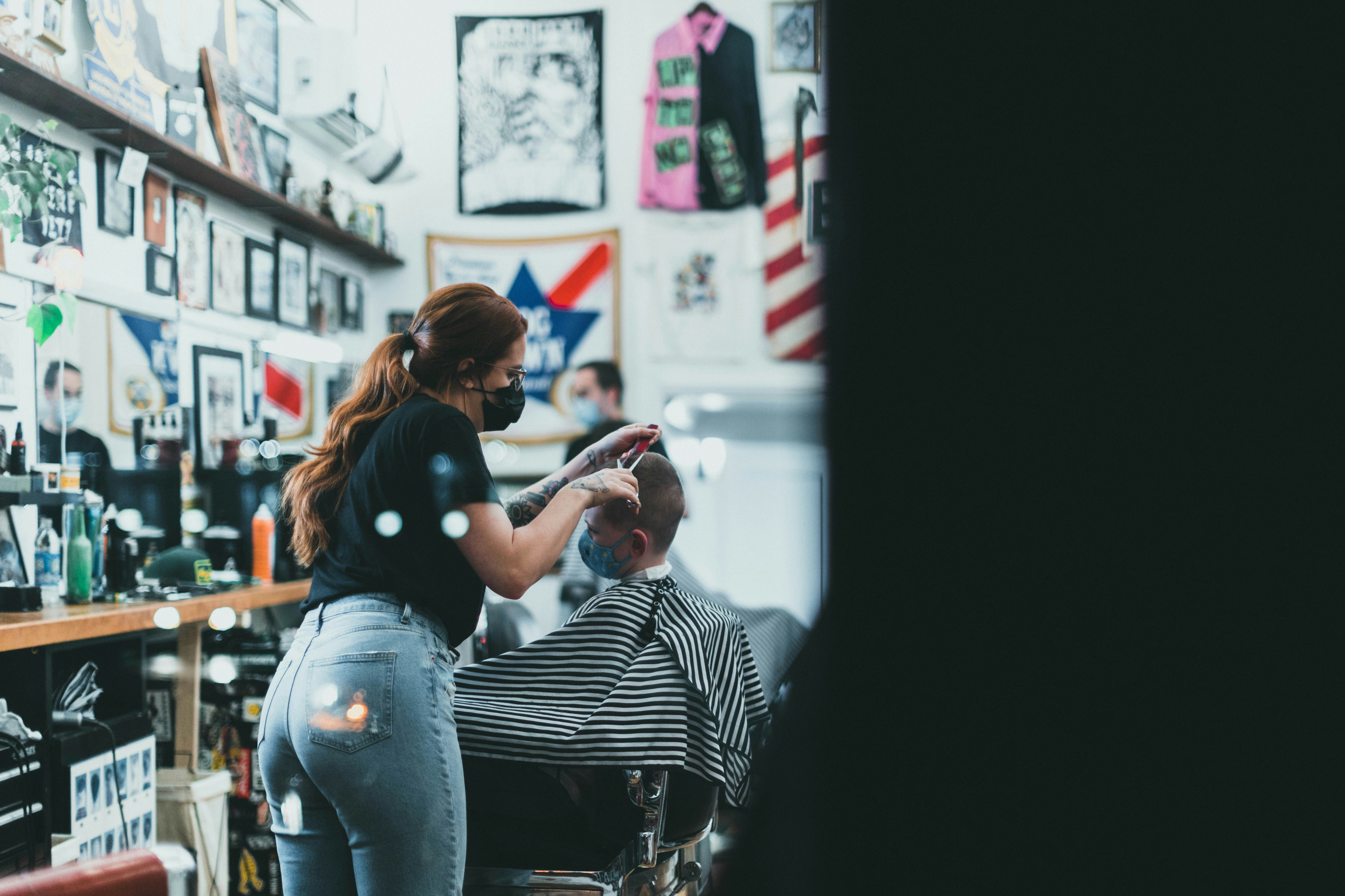 a woman cutting a mans hair in a barber shop