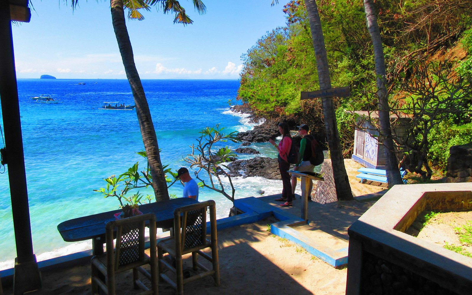 Snorkelers preparing at Blue Lagoon beach, Bali, with boats in the ocean.