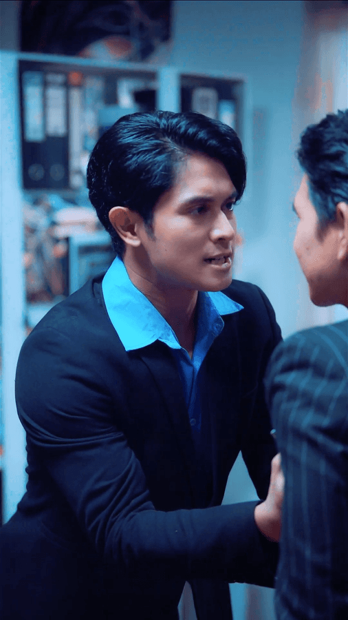 Luxury fashion editorial photography featuring model in vibrant patterned suit with orange accents, seated on vintage green armchair in elegant interior setting - Serif Creative Studio portfolio