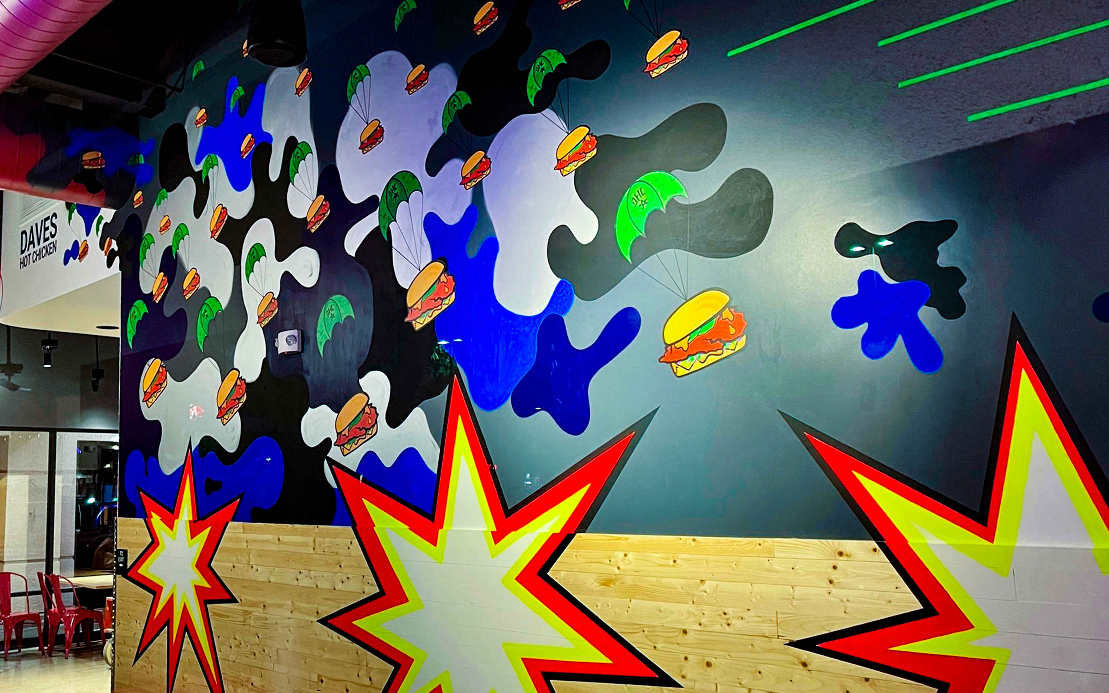 Large-scale burger mural with parachuting sliders and bold graphic shapes inside Dave’s Hot Chicken Port Hueneme.