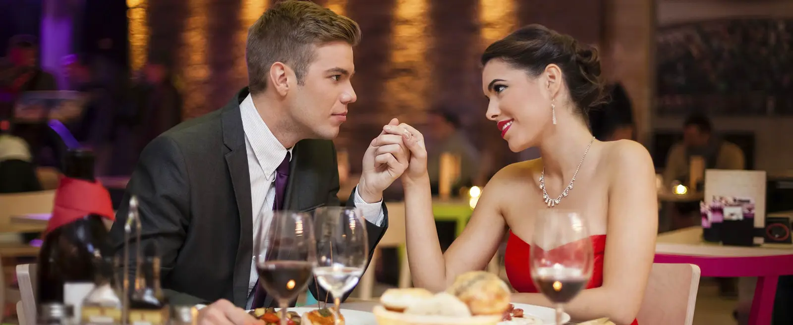 Formal couple holding hands at a restaurant table.