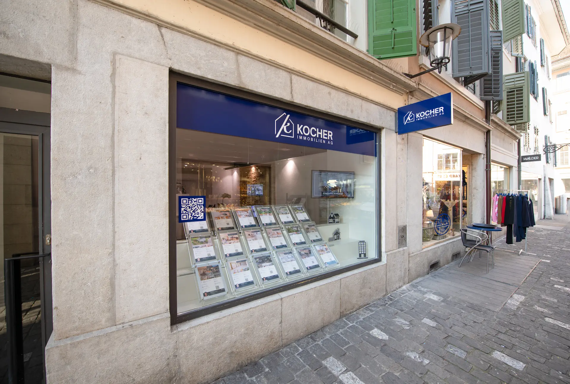 Gesamtes Team von Kocher Immobilien sitzt gemeinsam im Büro und lacht in moderner Umgebung