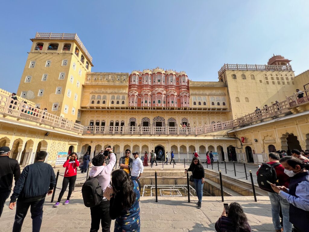 An open courtyard behind the Hawa Mahal facade of jharokas with a fountain