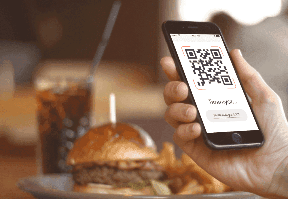 Restoranda telefonla QR menü kodunu tarayan müşteri