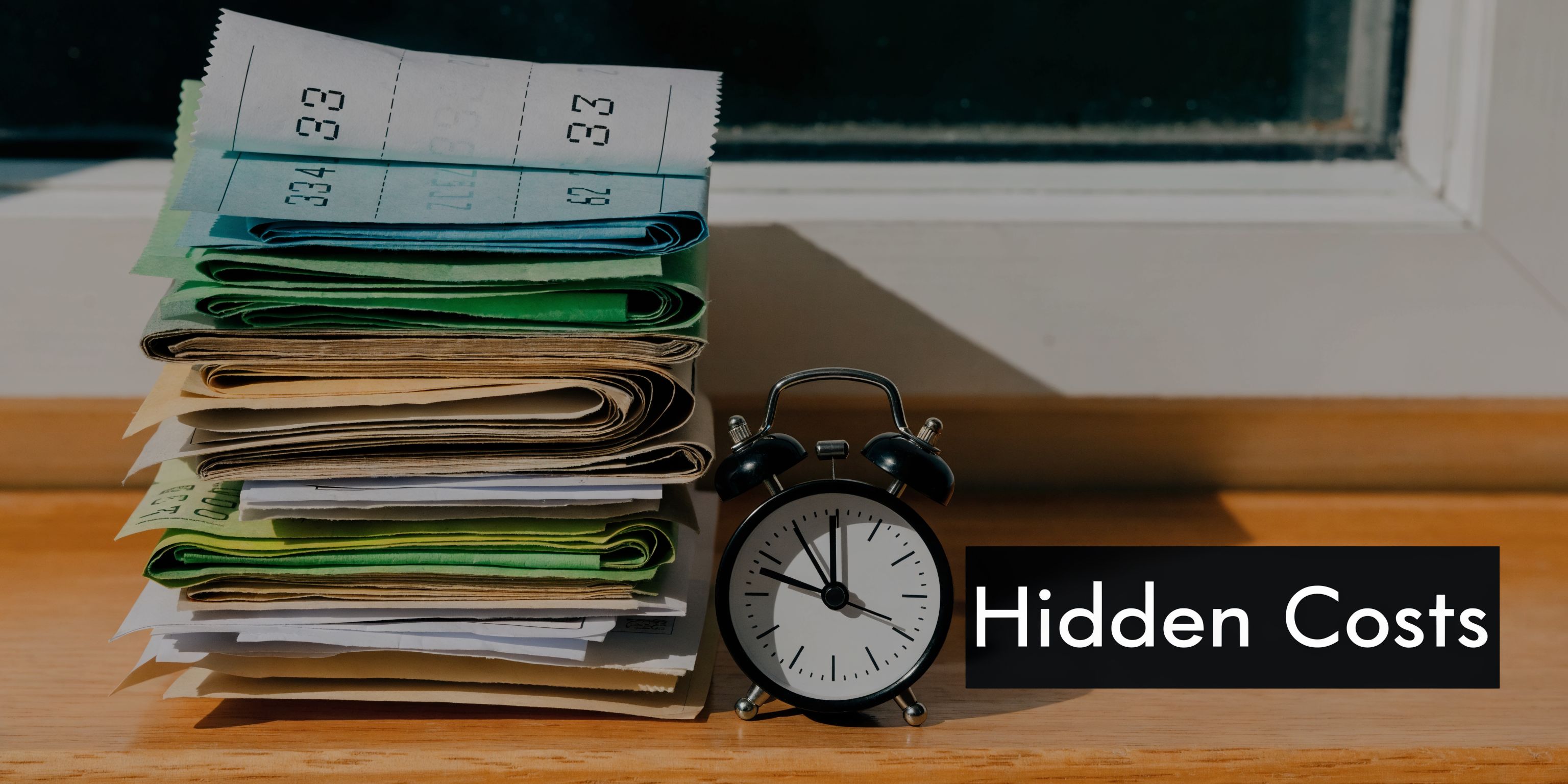 A stack of folded paper receipts next to a small black alarm clock on a wooden windowsill.