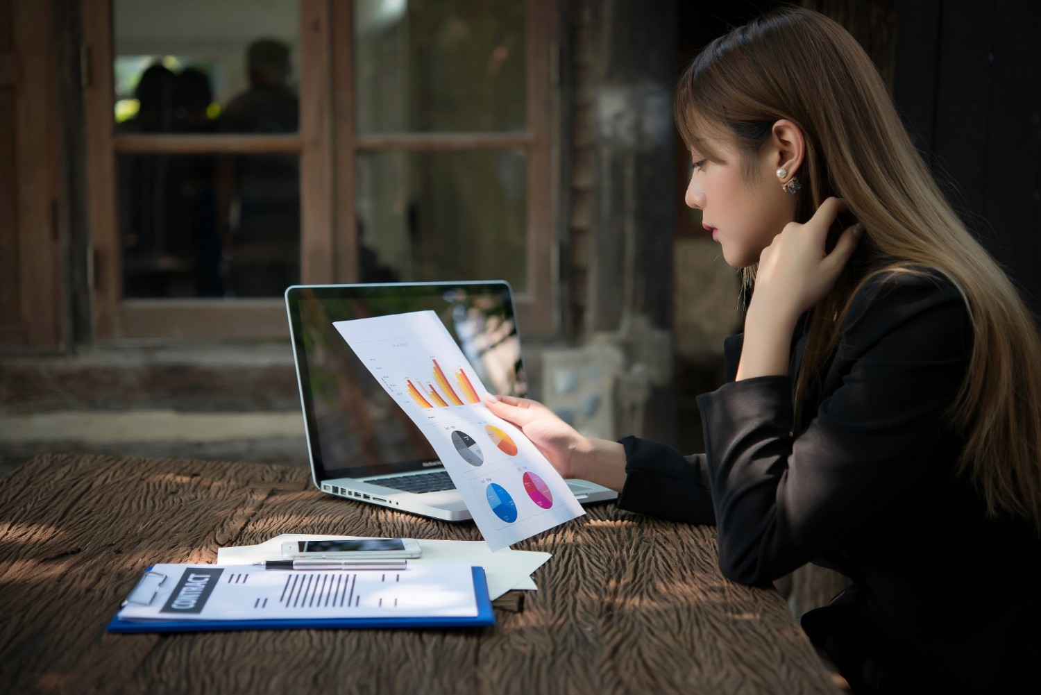  A professional woman in a business suit intently examines her laptop screen in a modern office setting.