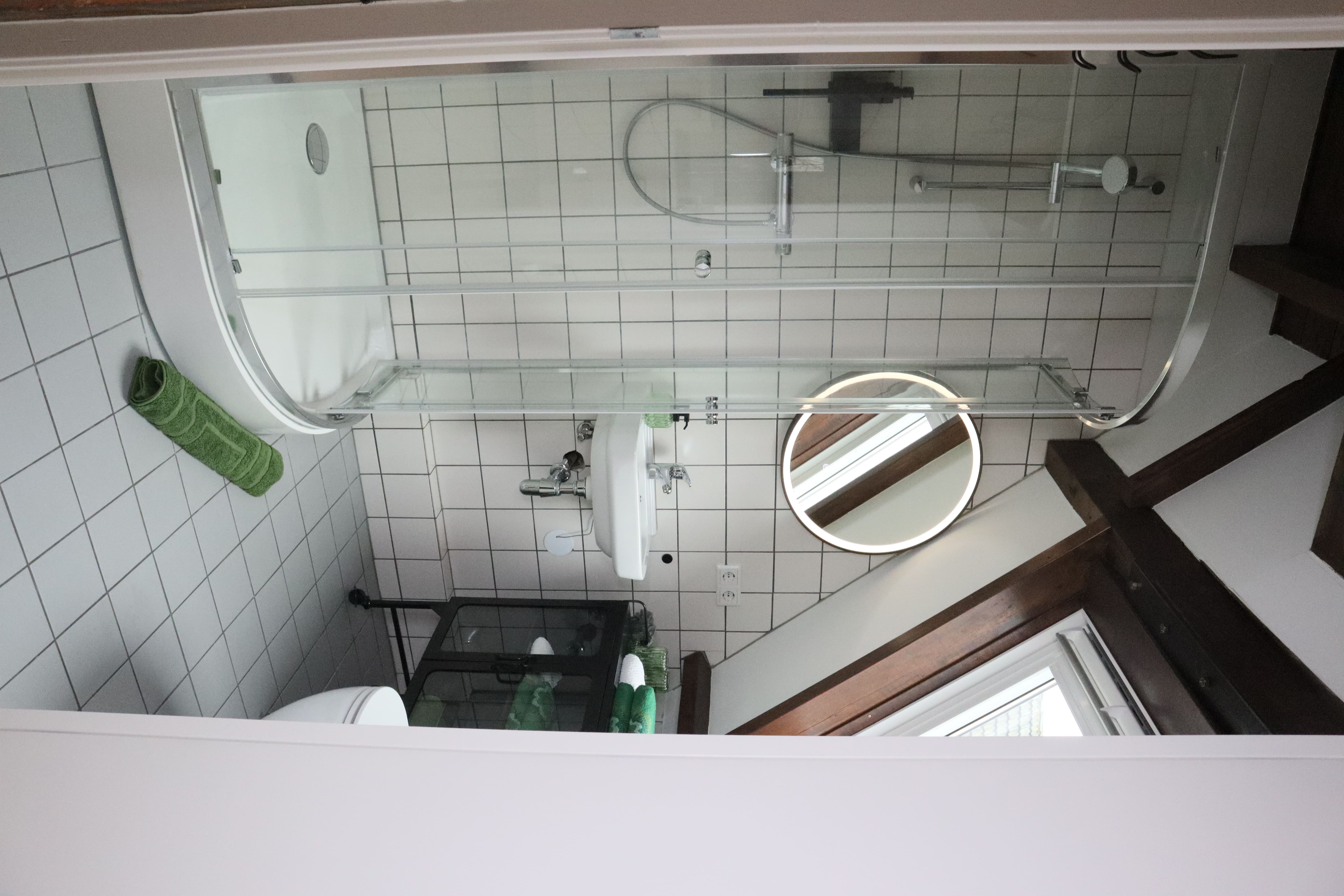 Uitzicht vanuit de bovenverdieping op de woonkamer, met houten balken en een trap.
