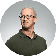 A man wearing glasses and a green polo shirt smiles at the camera